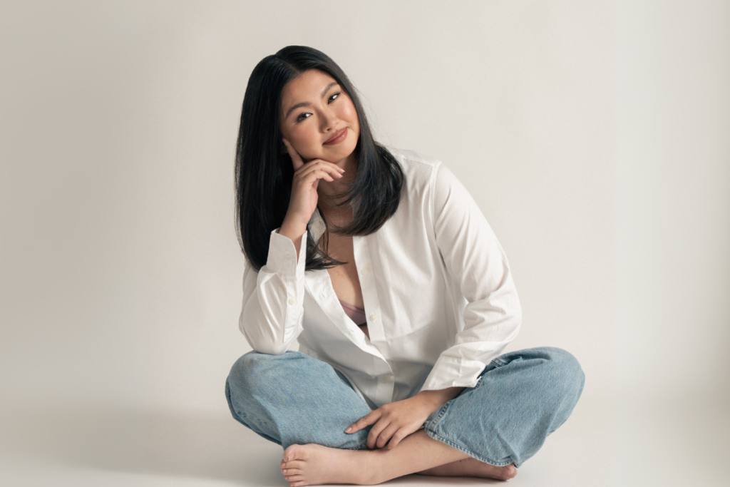 Giannina in a white shirt and jeans sitting on the floor